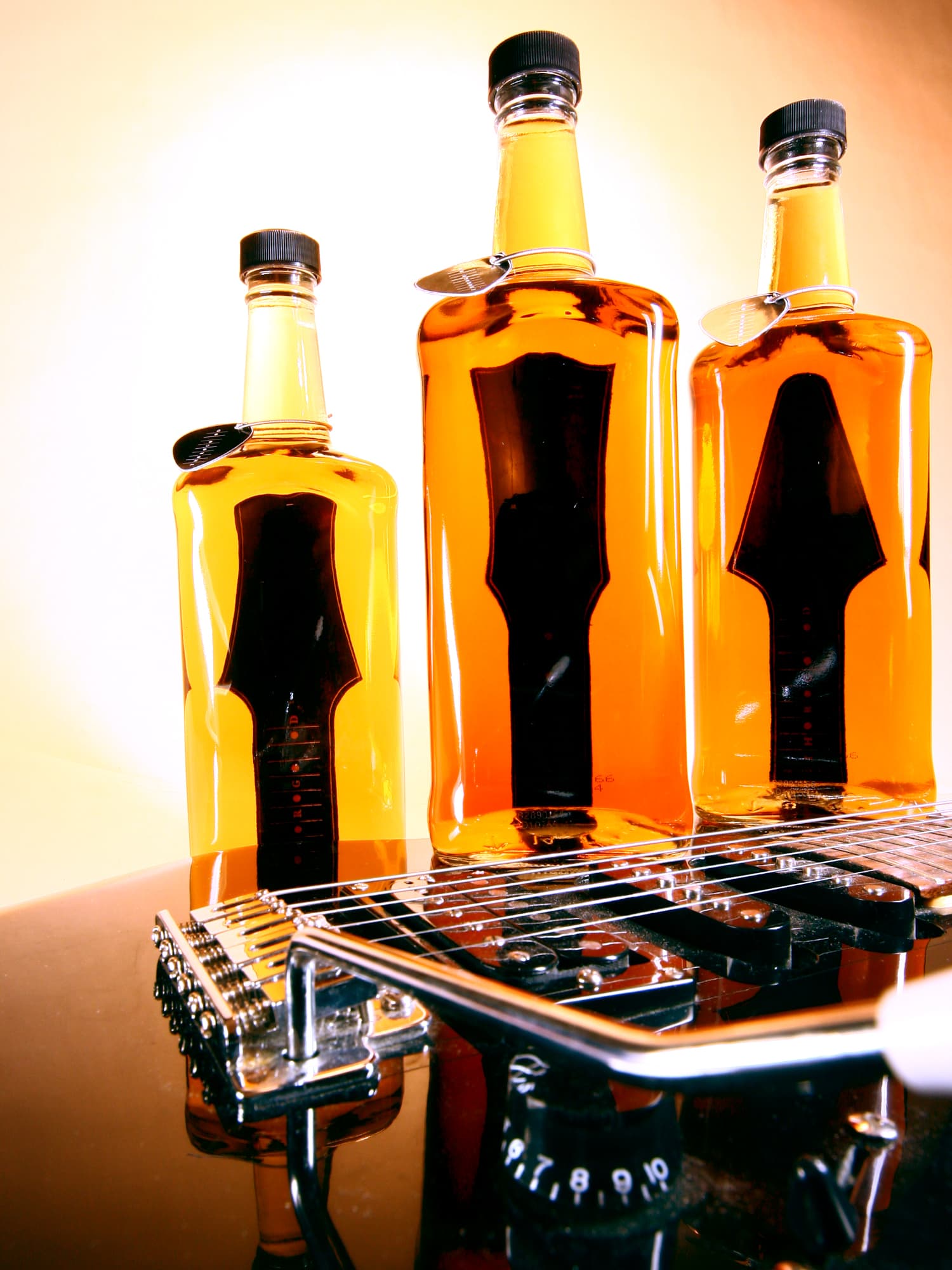 A photo of 3 bottles of whiskey and a guitar